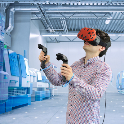 Mann mit VR-Brille und zwei Controllern in einer hellen Fabrikhalle mit Maschinen im Hintergrund